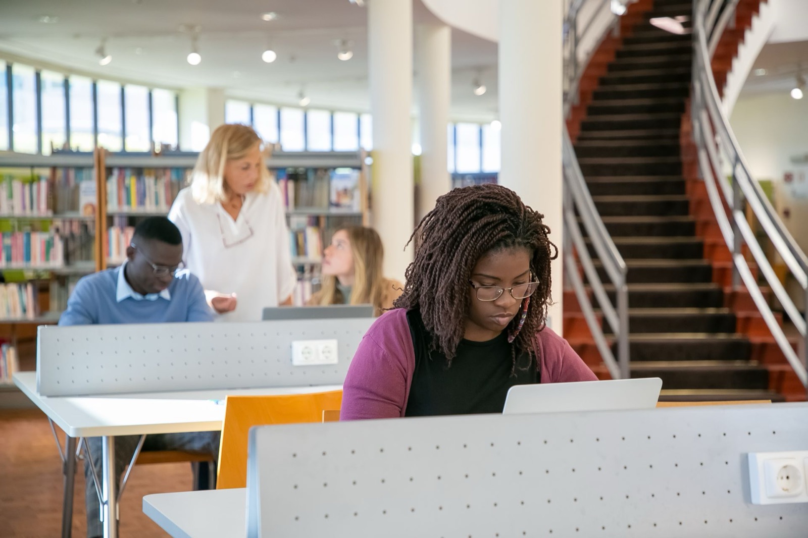 Students working on laptops at desks in a university library