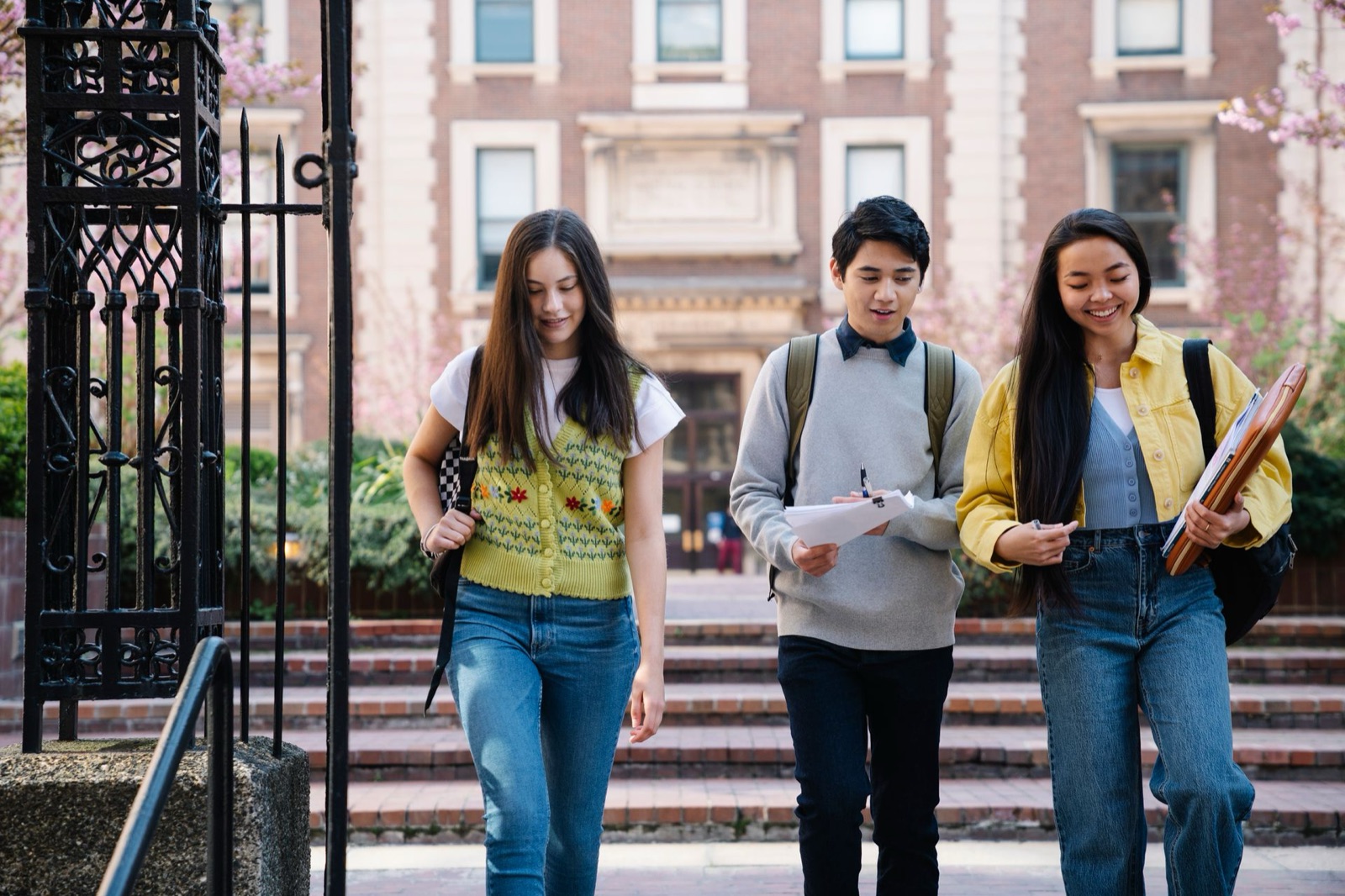 Three college students chatting while walking out of a campus gate