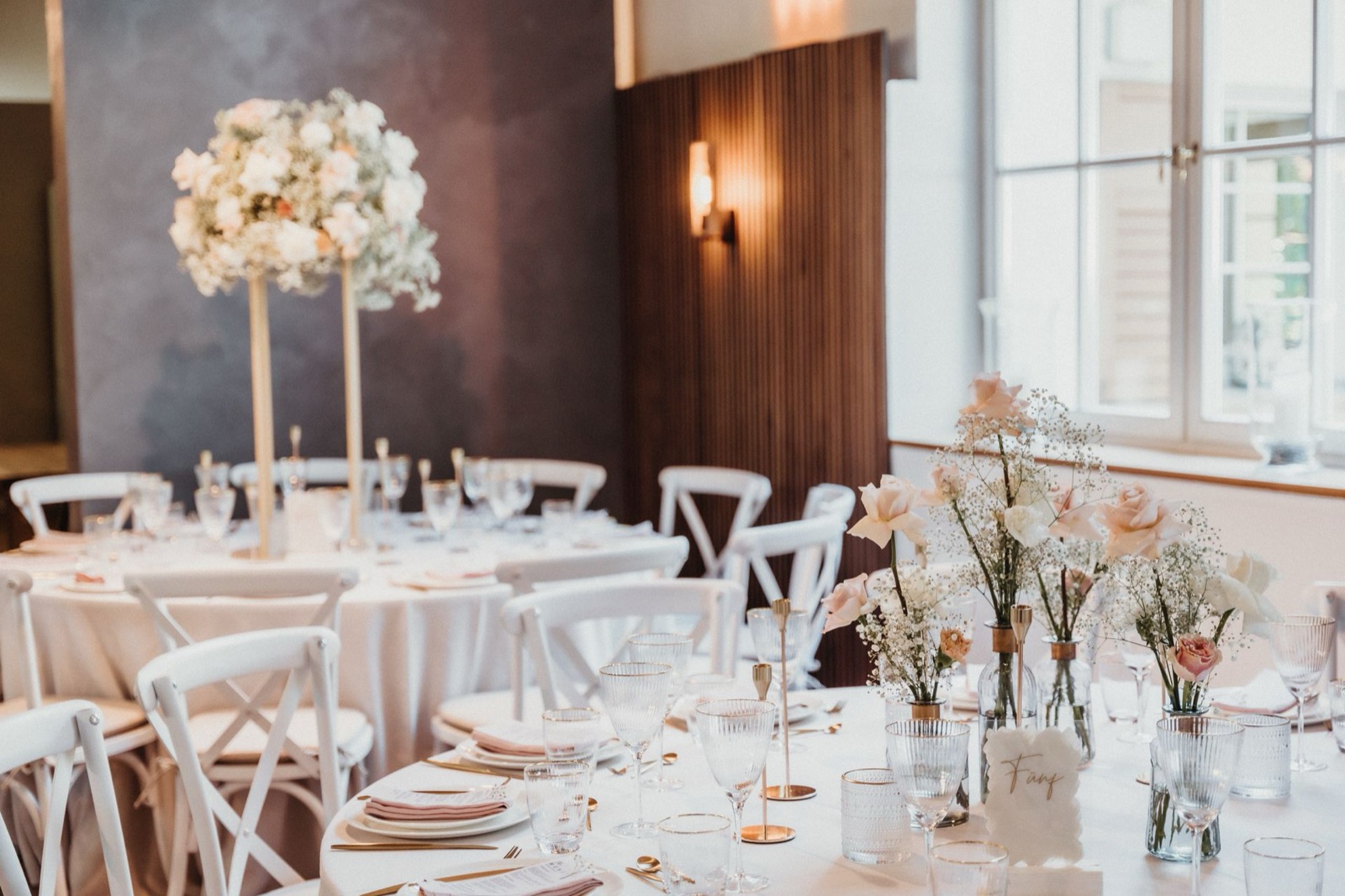 A wedding venue hall with set tables and flower centerpieces